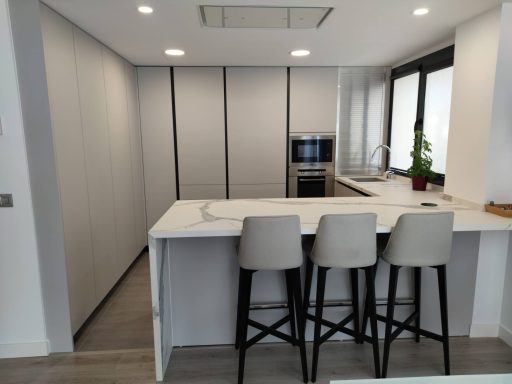 Cocina moderna con isla, barras altas y electrodomésticos integrados.